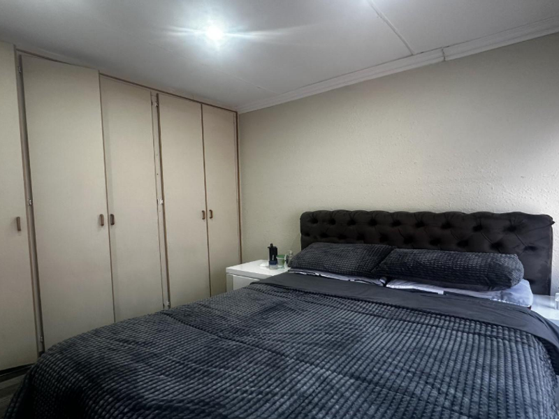A bedroom featuring a wall of built-in cupboards and neutral wall finishes, providing functional storage space.