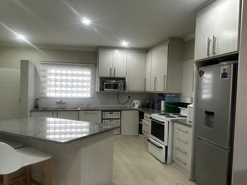 A functional kitchen featuring light-toned cabinetry, granite countertops, a central island, and recessed lighting, providing a clean and practical workspace.