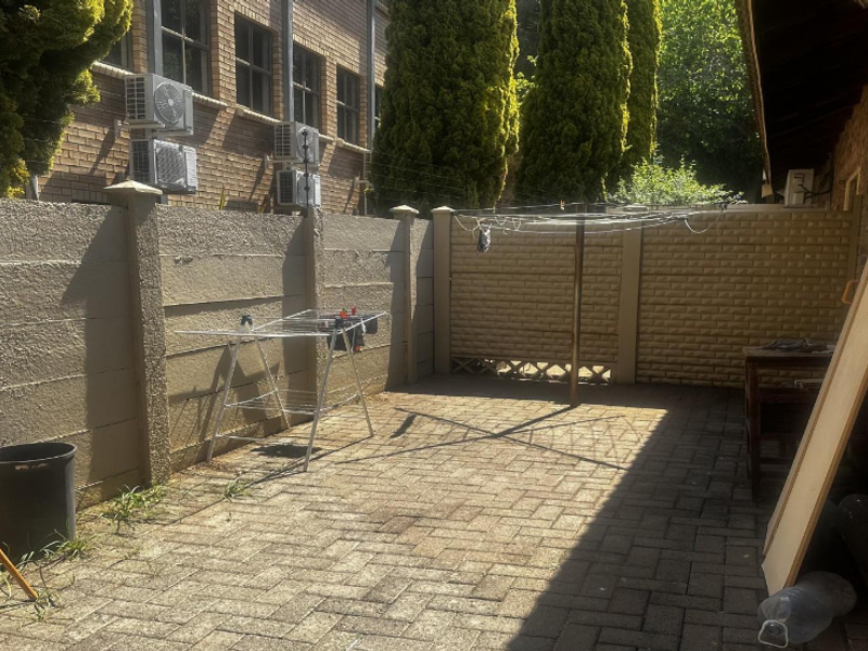 A paved rear courtyard area featuring a precast concrete boundary wall and a rotary clothesline, providing a functional outdoor utility space.