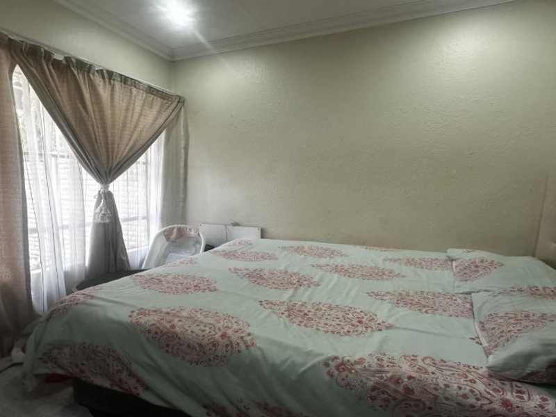 A standard bedroom featuring neutral wall finishes, a window with curtain treatments, and ceiling cornice detailing.