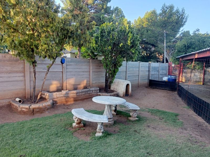 A private backyard garden featuring a precast concrete boundary wall, raised brick planters, and a fixed concrete outdoor seating area.