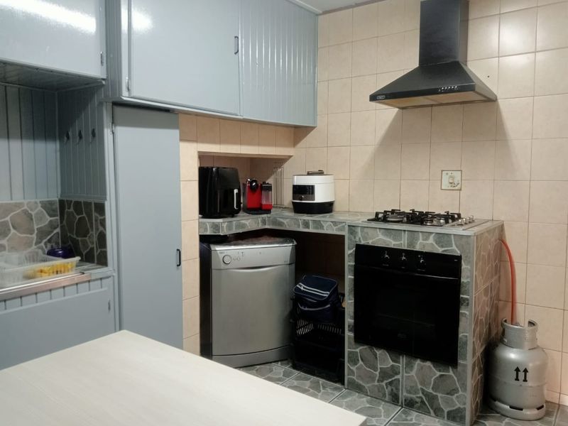 A functional kitchen featuring built-in cabinetry, a gas hob, an integrated oven, and a tiled splashback with stone-cladding accents.