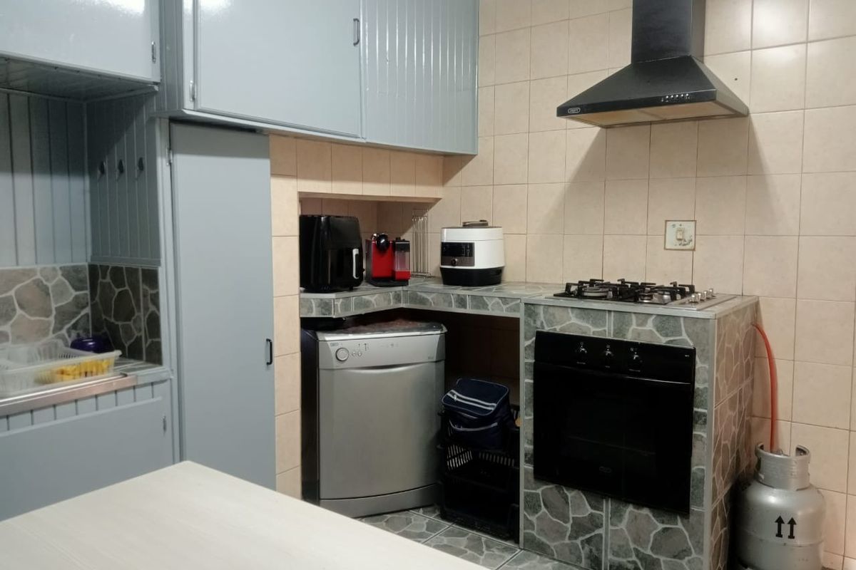 A functional kitchen featuring built-in cabinetry, a gas hob, an integrated oven, and a tiled splashback with stone-cladding accents.