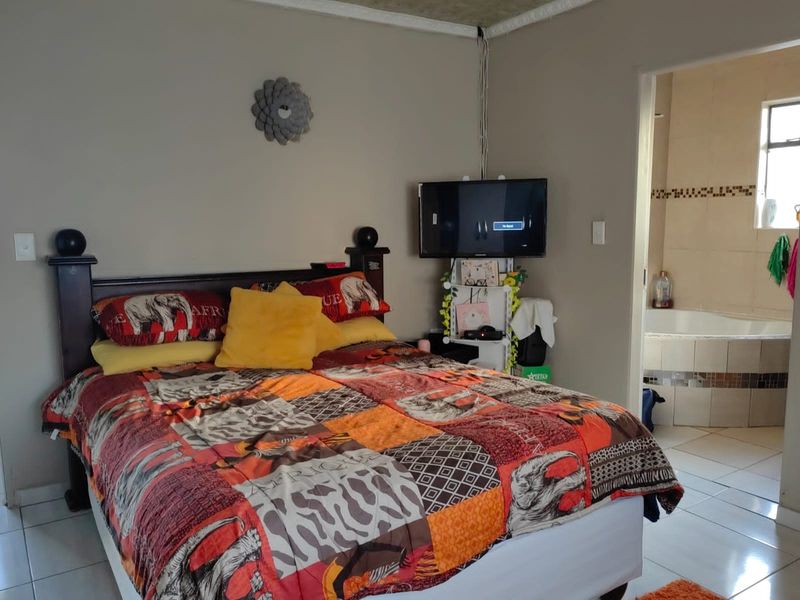 A bedroom featuring tiled flooring and coving, with an adjoining en-suite bathroom containing a built-in bathtub.
