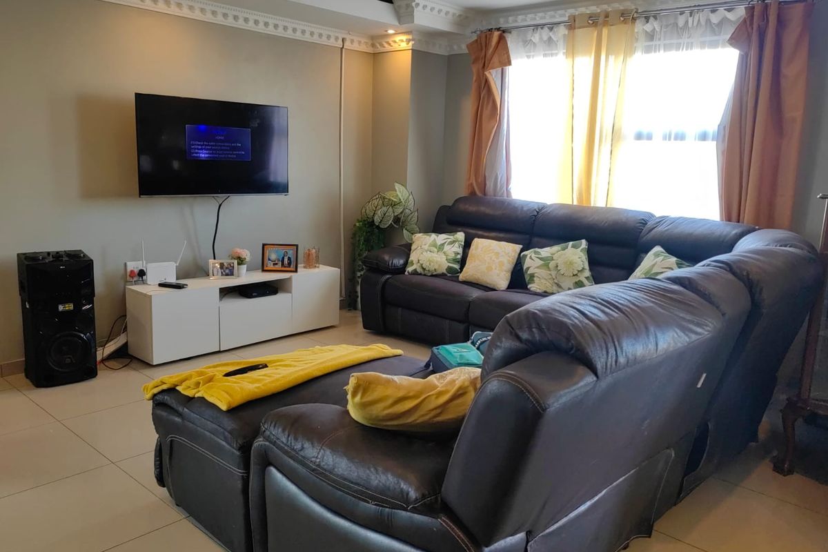A comfortable living room featuring tiled flooring, decorative crown molding, and recessed ceiling lighting, providing a functional and well-lit space for relaxation.