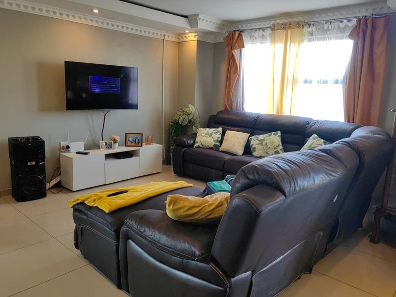 A comfortable living room featuring tiled flooring, decorative crown molding, and recessed ceiling lighting, providing a functional and well-lit space for relaxation.
