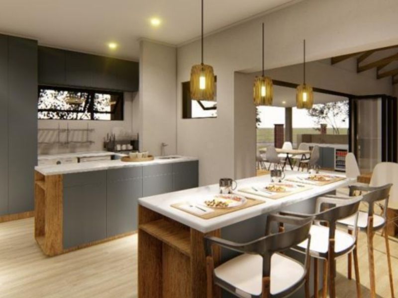 A modern open-plan kitchen and dining area featuring contemporary cabinetry, a central island with stone countertops, and seamless flow to the outdoor patio.