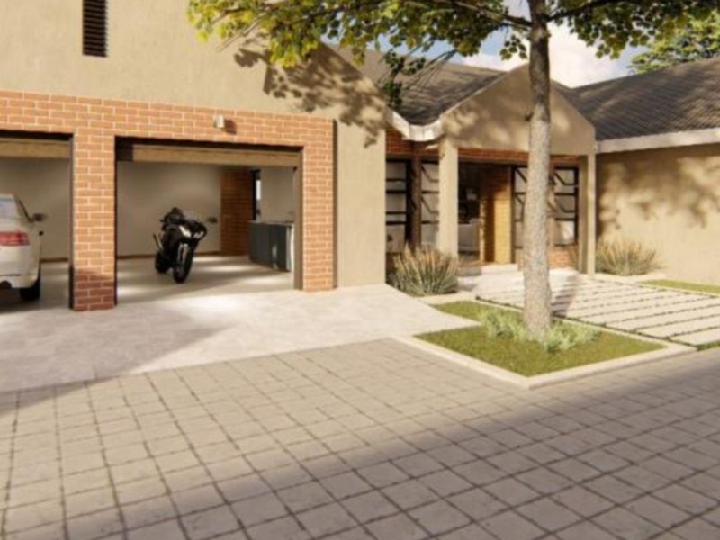 A modern residential front elevation featuring a double garage, brick detailing, and a neatly paved driveway with landscaped garden elements.
