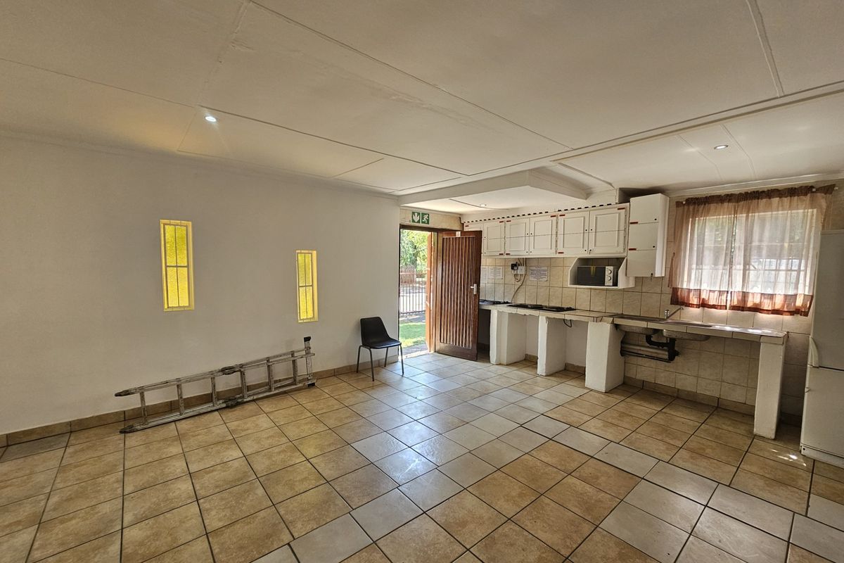 An open-plan kitchen area featuring tiled flooring, built-in cabinetry, and a tiled backsplash, offering a functional space ready for modernization.