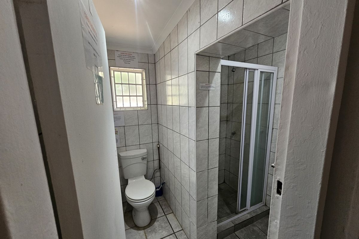A functional bathroom featuring a toilet and a separate shower enclosure with tiled walls and flooring.