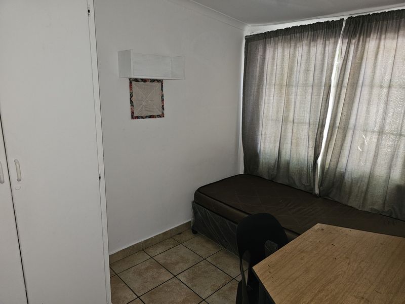 A functional bedroom featuring tiled flooring and a built-in wardrobe, offering a neutral space ready for personalization.