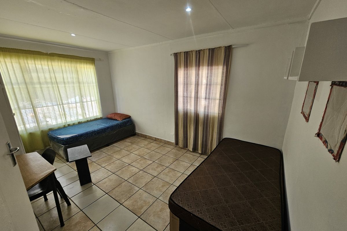 A functional bedroom featuring tiled flooring, recessed downlighting, and dual windows with installed curtain rails.