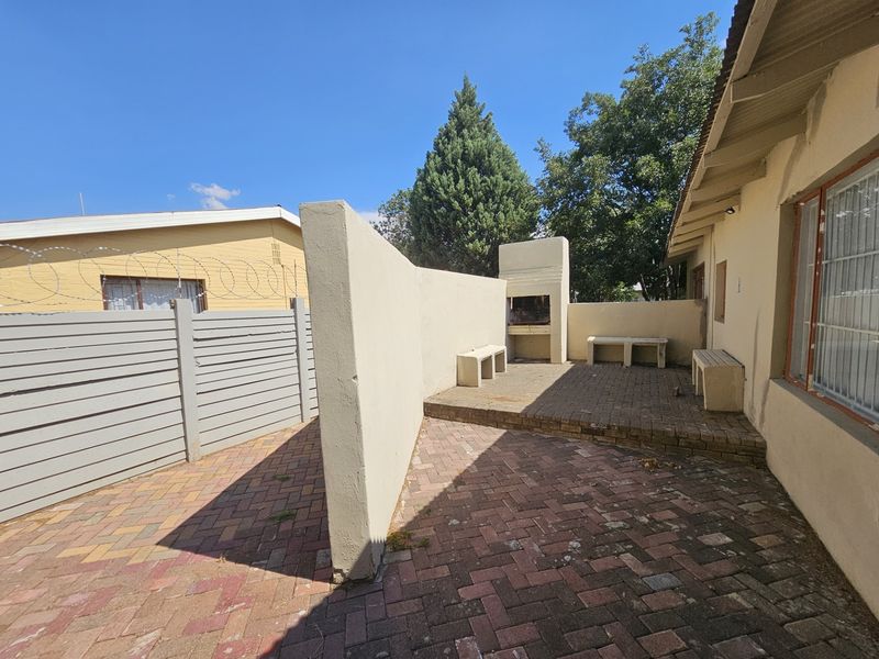 Outdoor patio area featuring a built-in braai, concrete bench seating, and paved flooring, providing a functional space for outdoor entertaining.