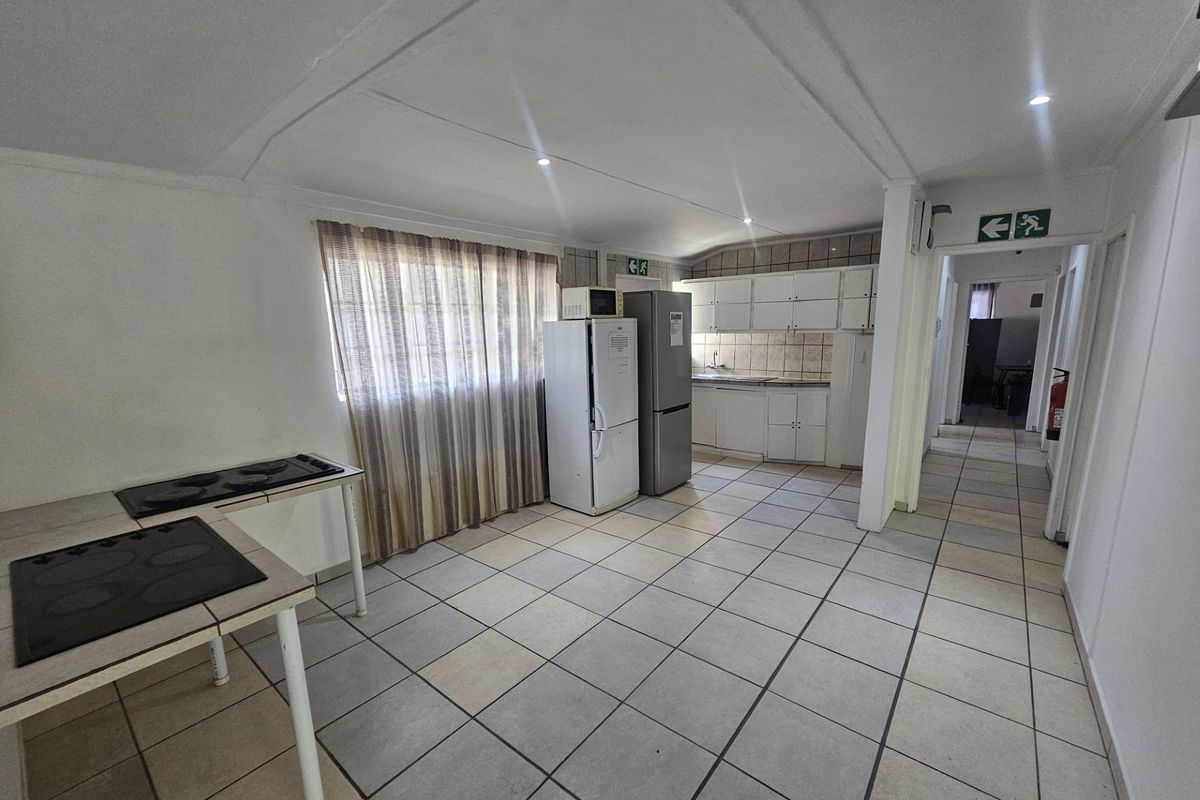 A functional kitchen area featuring tiled flooring, built-in cabinetry, and integrated hobs, offering a practical layout with potential for modern updates.