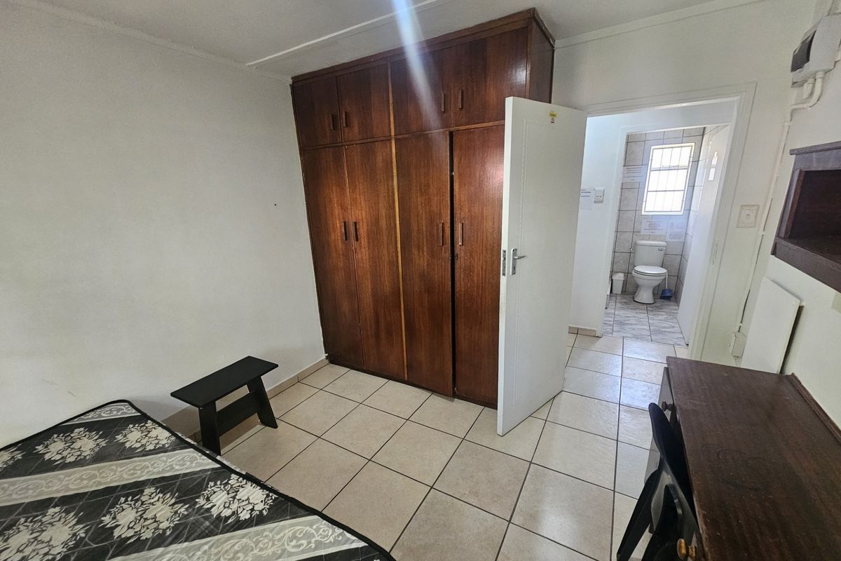 Bedroom featuring tiled flooring and a large built-in wooden wardrobe, with direct access to an en-suite bathroom.