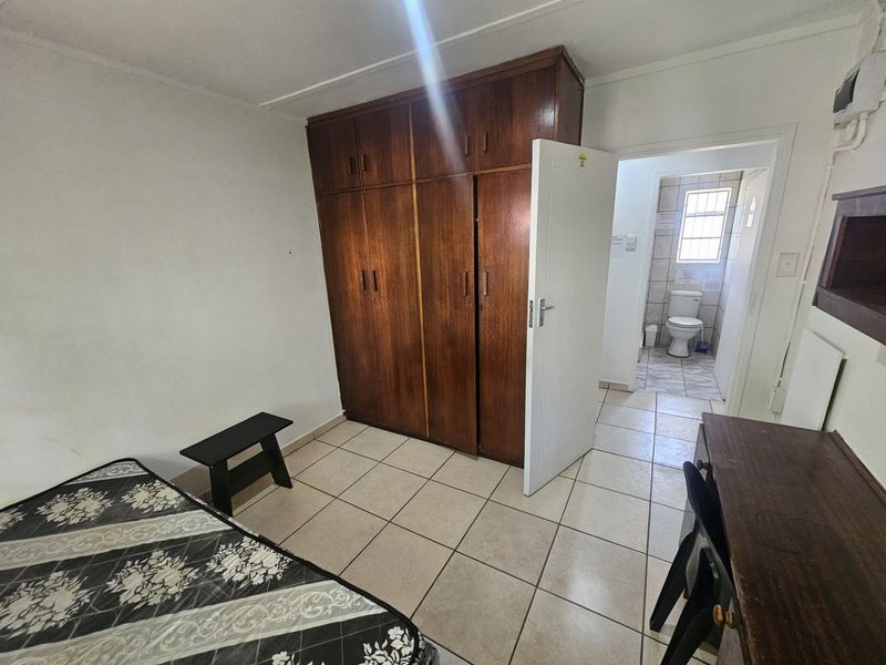 Bedroom featuring tiled flooring and a large built-in wooden wardrobe, with direct access to an en-suite bathroom.