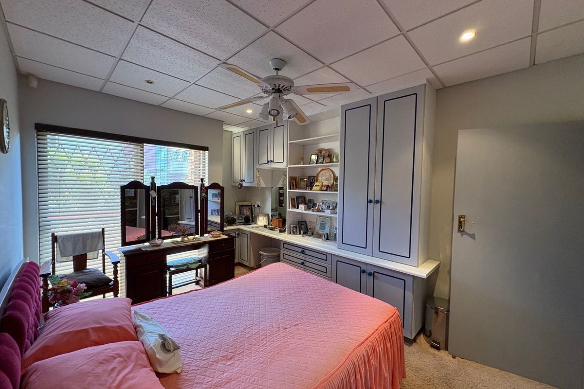 A bedroom featuring extensive built-in cabinetry, a ceiling fan, and a drop ceiling with recessed lighting.