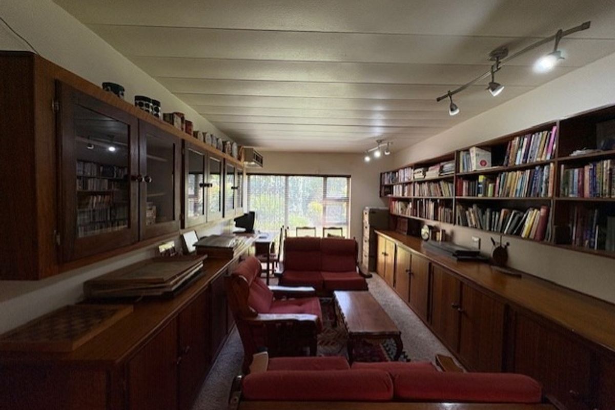 A living room featuring extensive built-in wooden cabinetry and shelving, track lighting, and a sliding glass door providing natural light.