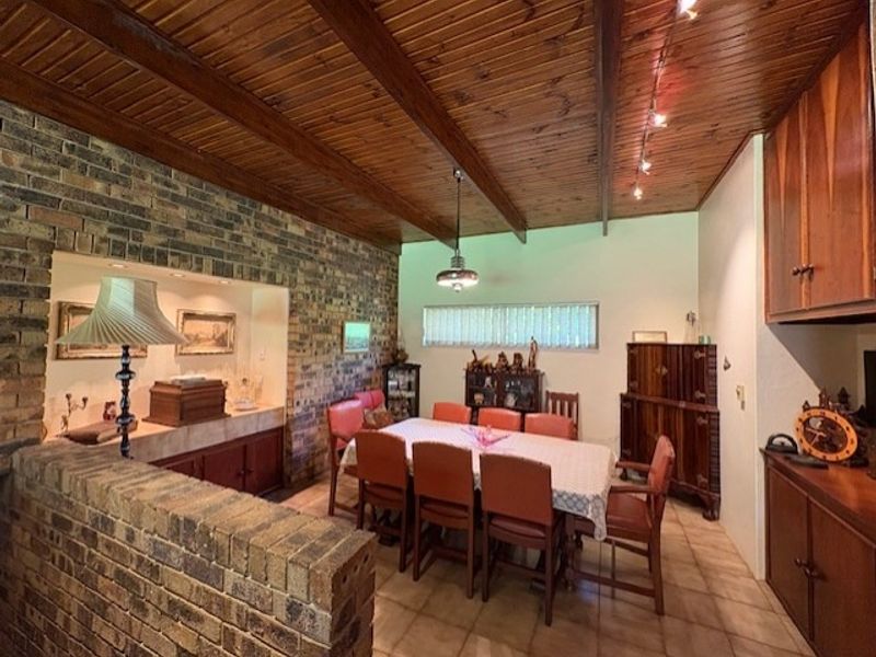 Dining room featuring a timber tongue and groove ceiling with exposed beams, an exposed brick feature wall, and built-in cabinetry.