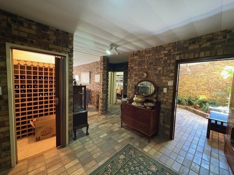 Entrance hall featuring exposed brick walls, tiled flooring, and direct access to a built-in wine cellar and an internal courtyard.