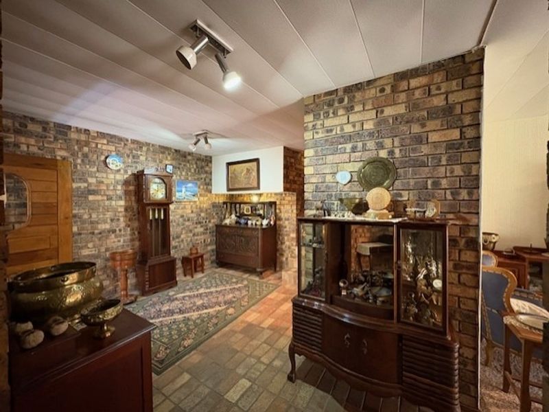 A living area featuring rustic exposed brick walls, tiled flooring, and functional track lighting, offering a traditional aesthetic.