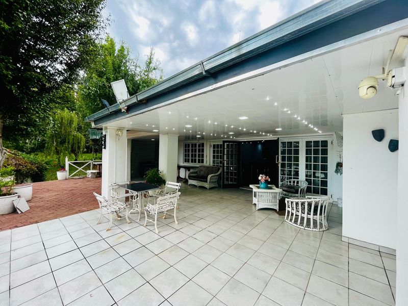 A spacious covered patio featuring tiled flooring, recessed ceiling lights, and direct access to the home through multiple sets of french doors.