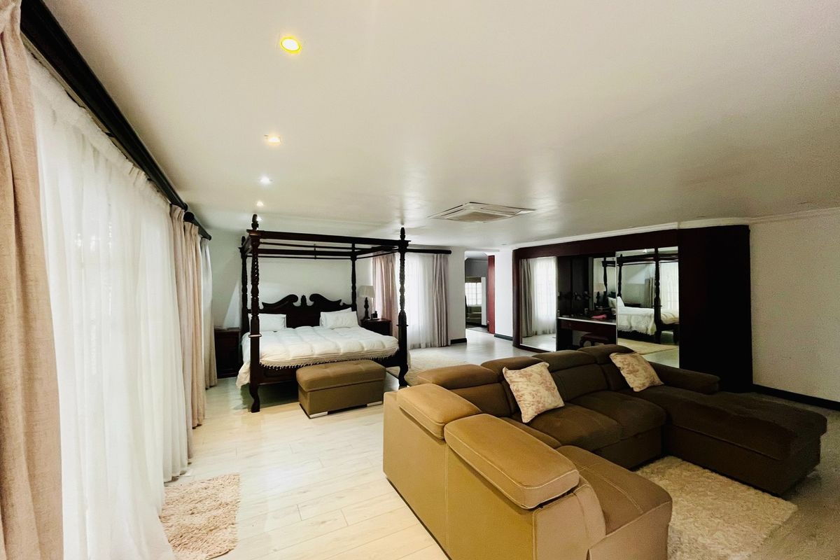 Spacious bedroom featuring tiled flooring, recessed lighting, ceiling-mounted air conditioning, and extensive built-in cabinetry with mirrored doors.