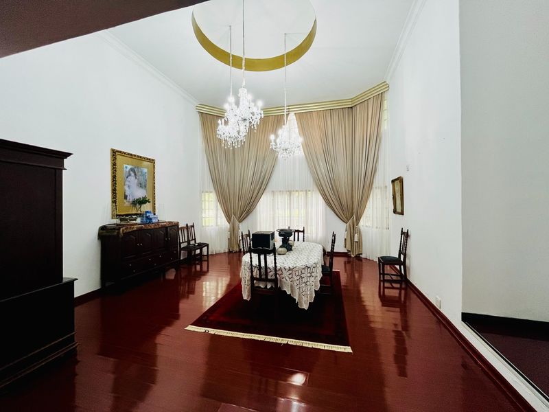 Spacious formal dining room featuring polished hardwood flooring, high ceilings with recessed architectural detail, and elegant crystal chandeliers.