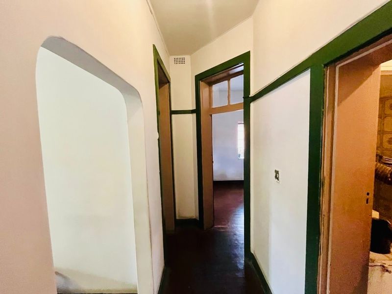A functional hallway featuring timber door frames, an arched entryway, and original timber flooring, connecting multiple rooms within the townhouse.