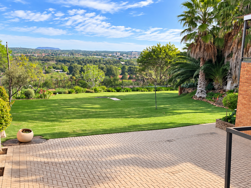 A spacious rear garden featuring brick paving, a well-maintained lawn, and expansive elevated views over the surrounding landscape.