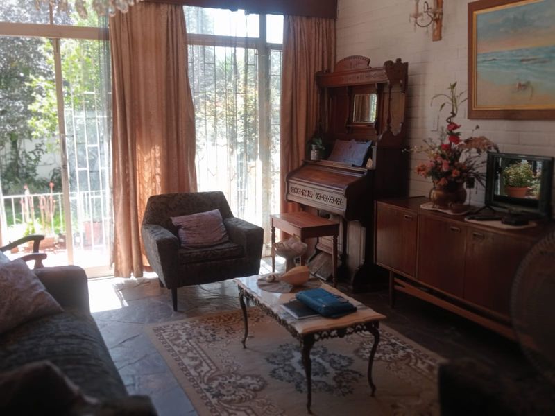 A living room featuring stone flooring, painted brick walls, and large sliding glass doors with security bars providing access to the garden.