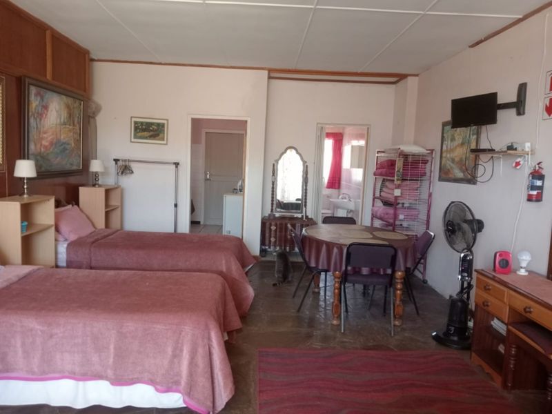 A spacious bedroom featuring tiled flooring and direct access to an en-suite bathroom, offering a functional layout with potential for cosmetic updates.