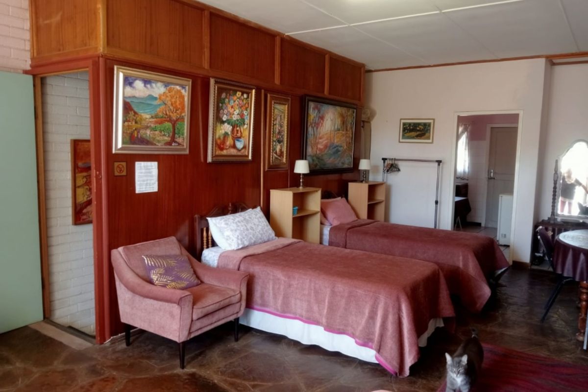A bedroom featuring wood-paneled walls and stone tile flooring, offering a traditional aesthetic with potential for modern updates.