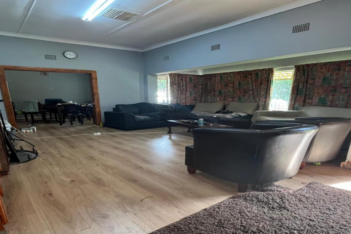 Spacious living room featuring laminate flooring and neutral wall tones, offering a versatile layout for comfortable family living.