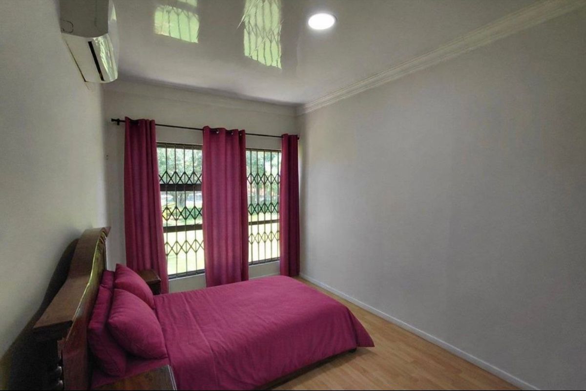 A bedroom featuring laminate flooring, recessed ceiling lighting, a split-system air conditioner, and windows fitted with security gates.