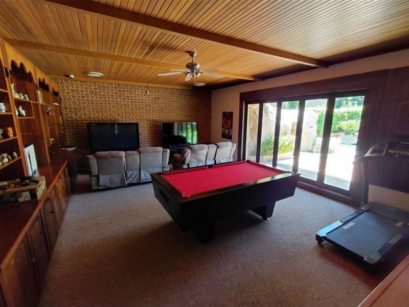 Spacious living area featuring a timber-clad ceiling, exposed brick wall, built-in cabinetry, and large sliding glass doors providing access to the outdoor area.