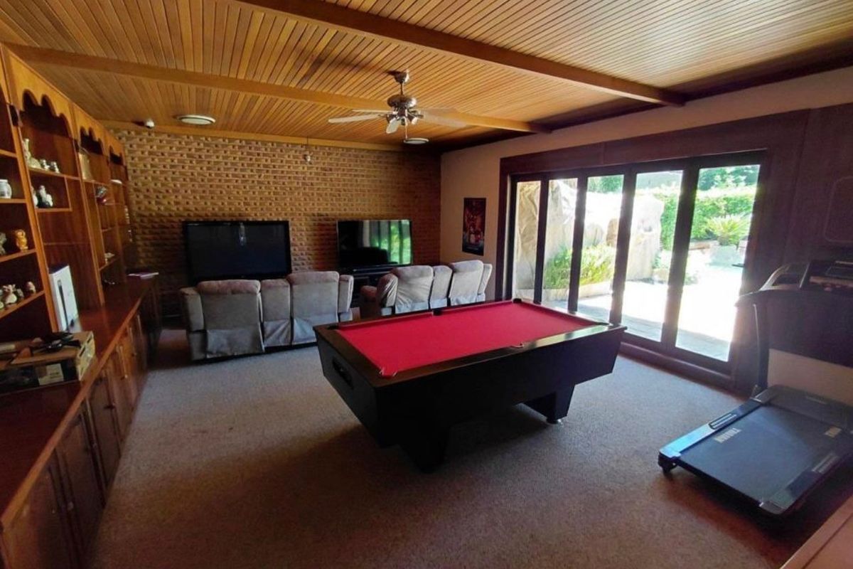 Spacious living area featuring a timber-clad ceiling, exposed brick wall, built-in cabinetry, and large sliding glass doors providing access to the outdoor area.
