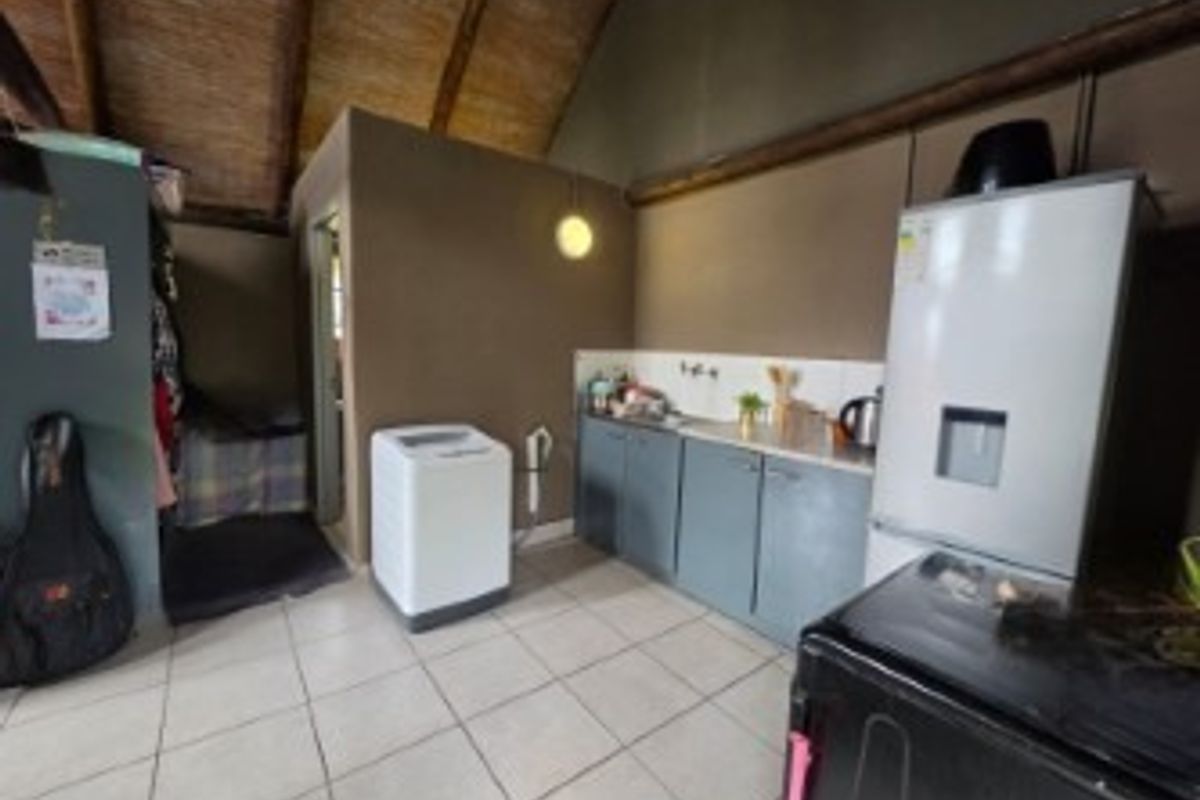 A compact kitchen area featuring tiled flooring, built-in cabinetry, and exposed timber ceiling beams, offering a functional layout with potential for modernization.