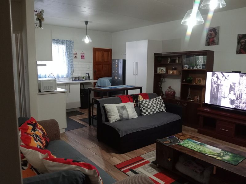 Open-plan living area featuring a functional kitchen with cabinetry and tiled flooring, seamlessly connected to the lounge space.