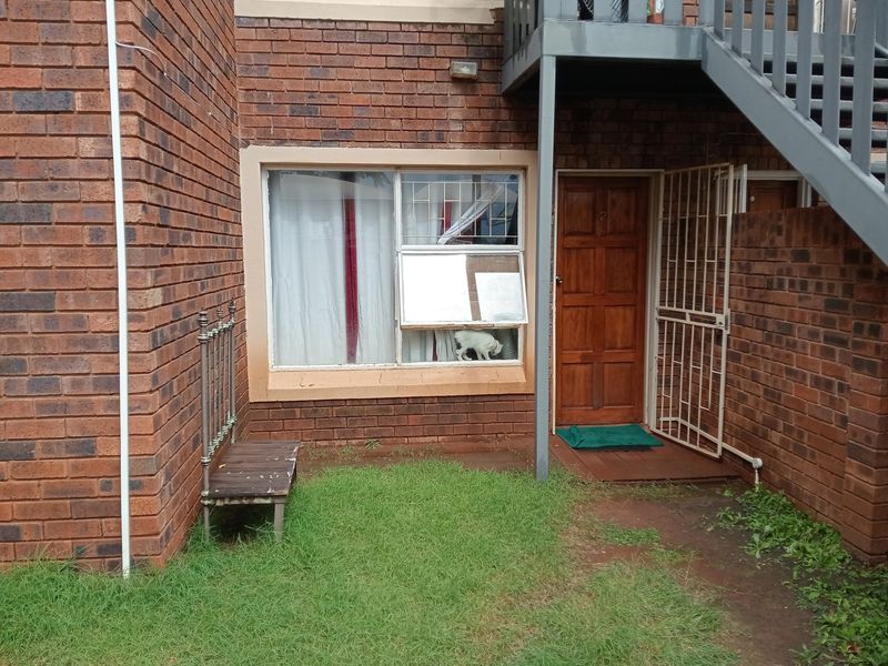 Front entrance of a townhouse featuring a brick facade, security gate, and external staircase access.