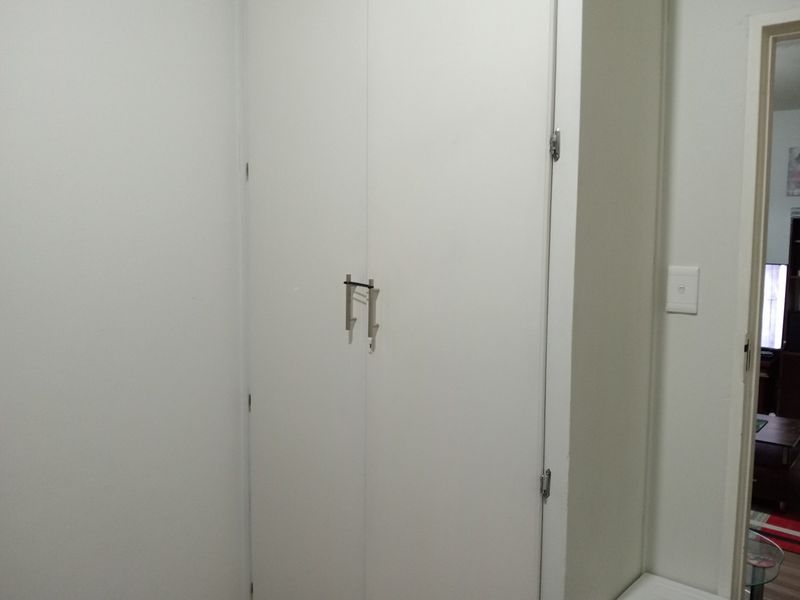A view of a bedroom featuring a white built-in cupboard with modern handles.