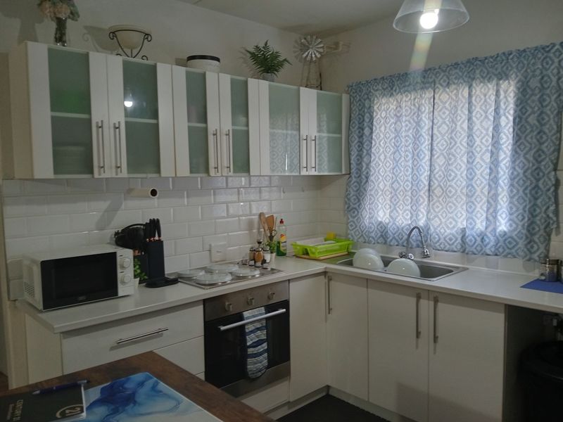 A functional kitchen featuring white cabinetry, subway tile backsplash, integrated stainless steel oven and hob, and a stainless steel sink with a mixer tap.