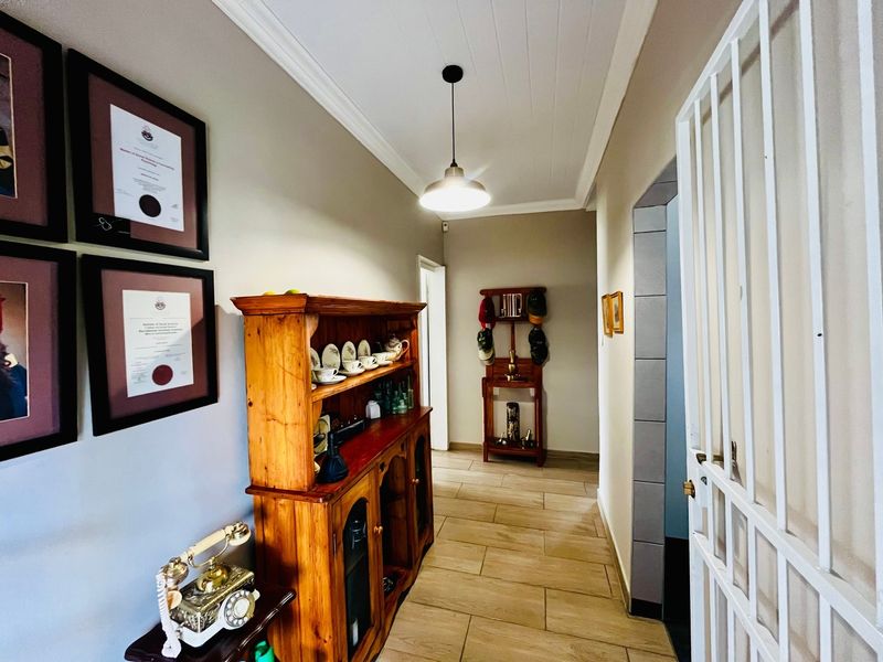 A well-maintained hallway featuring tiled flooring, a tongue and groove ceiling with pendant lighting, and a secure metal gate.