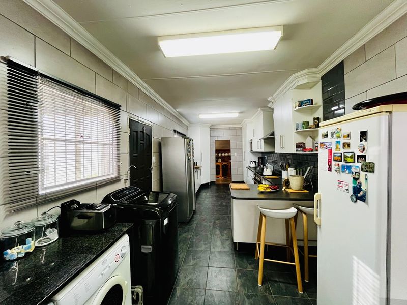 A functional kitchen featuring dark tiled flooring, white cabinetry, granite countertops, and tiled wall finishes with integrated appliance spaces.