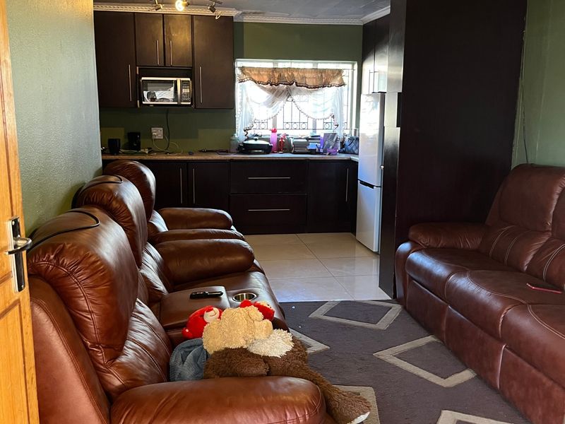 Open-plan living area featuring tiled flooring, dark built-in kitchen cabinetry, and a ceiling fan, creating a combined kitchen and lounge space.