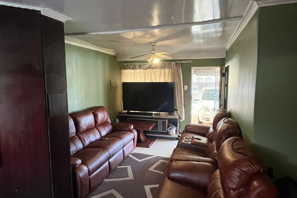 A living room featuring tiled flooring, a ceiling fan, and decorative ceiling cornices, with direct access to the exterior.