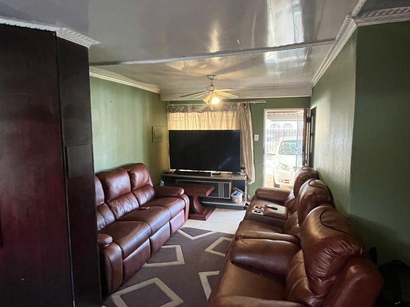 A living room featuring tiled flooring, a ceiling fan, and decorative ceiling cornices, with direct access to the exterior.