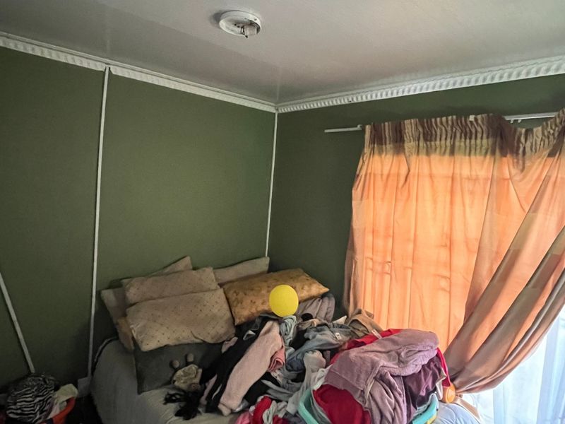 A bedroom featuring green walls and decorative crown molding, providing a functional space for rest.