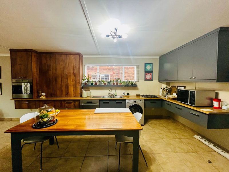 A functional kitchen featuring a mix of wooden and grey cabinetry, wooden countertops, built-in oven, gas hob, and tiled flooring.