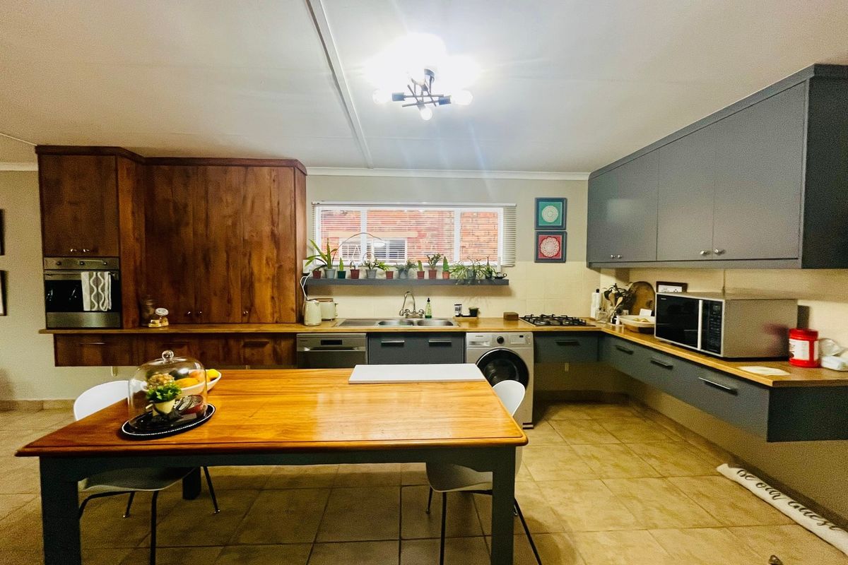A functional kitchen featuring a mix of wooden and grey cabinetry, wooden countertops, built-in oven, gas hob, and tiled flooring.